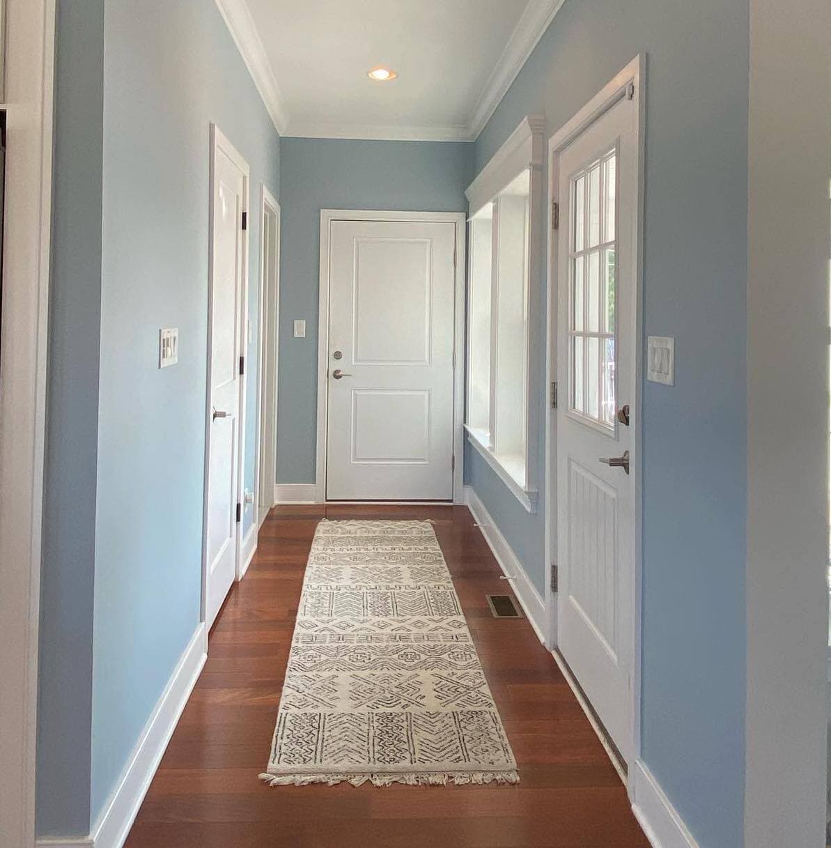 Finished blue painted hallway with white doors and trim