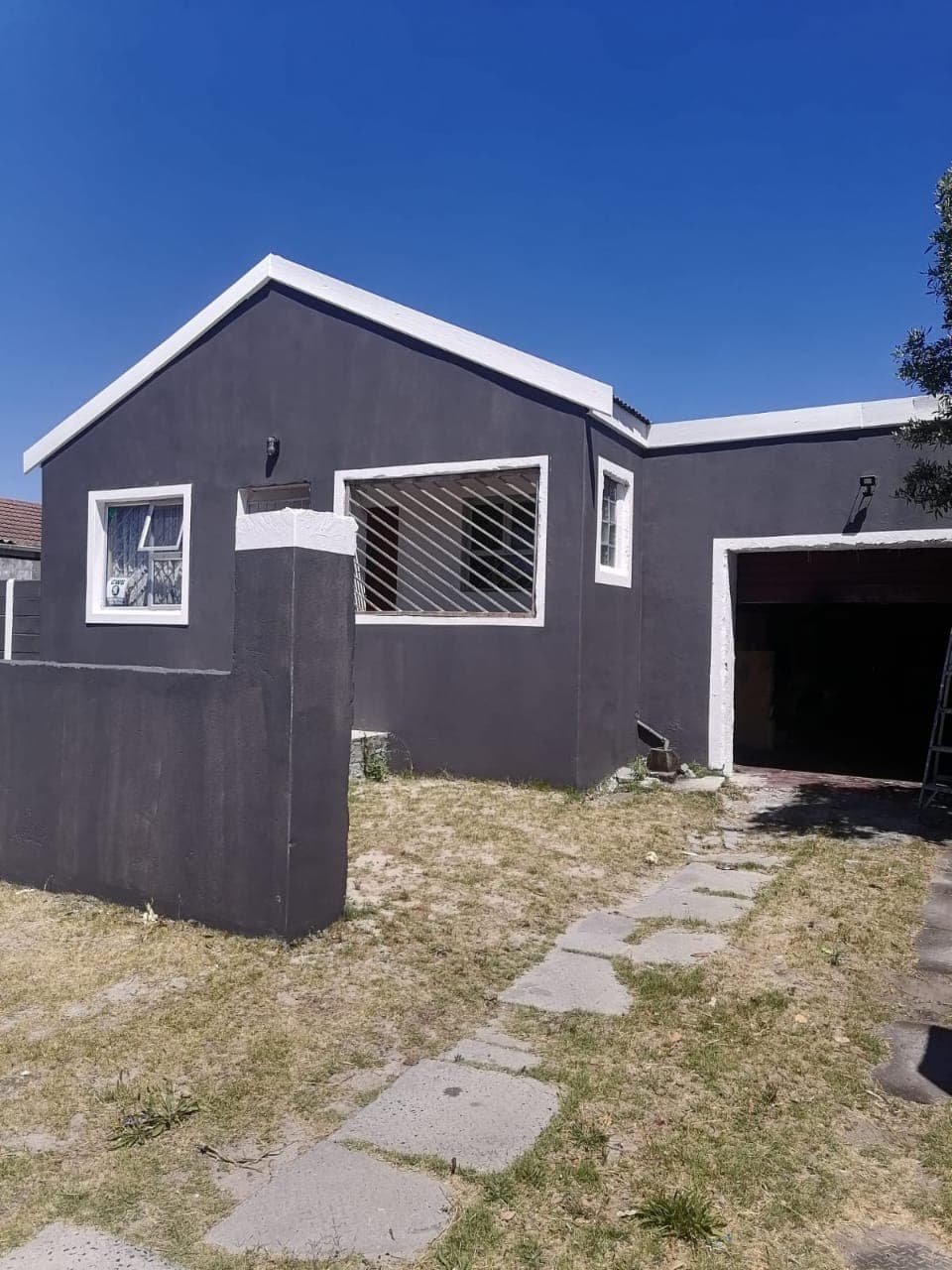 Freshly plastered and painted grey house exterior with white trim