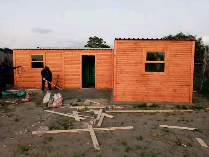 Two Wendy houses under construction with worker on site